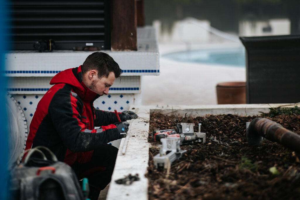 PHOTO D'UN PROFESSIONNEL DU SCIAGE BÉTON ENTRAIN DE TRACER DES MESURES SUR UN MURET BÉTON